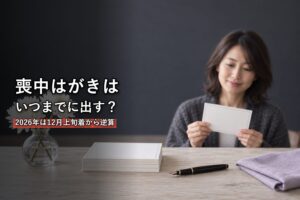 白菊と無地のはがきを前に喪中はがきを準備する女性